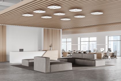 Corner of modern office waiting room with white and wooden walls, concrete floor, gray sofas and reception desk. Open space office in the background. 3d rendering